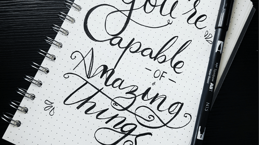 Image of a bullet journal perfect for mindful organization with writing that says "You're Capable of Amazing Things" written in calligraphy.