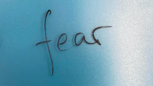 Image of the word fear written on a blue wall